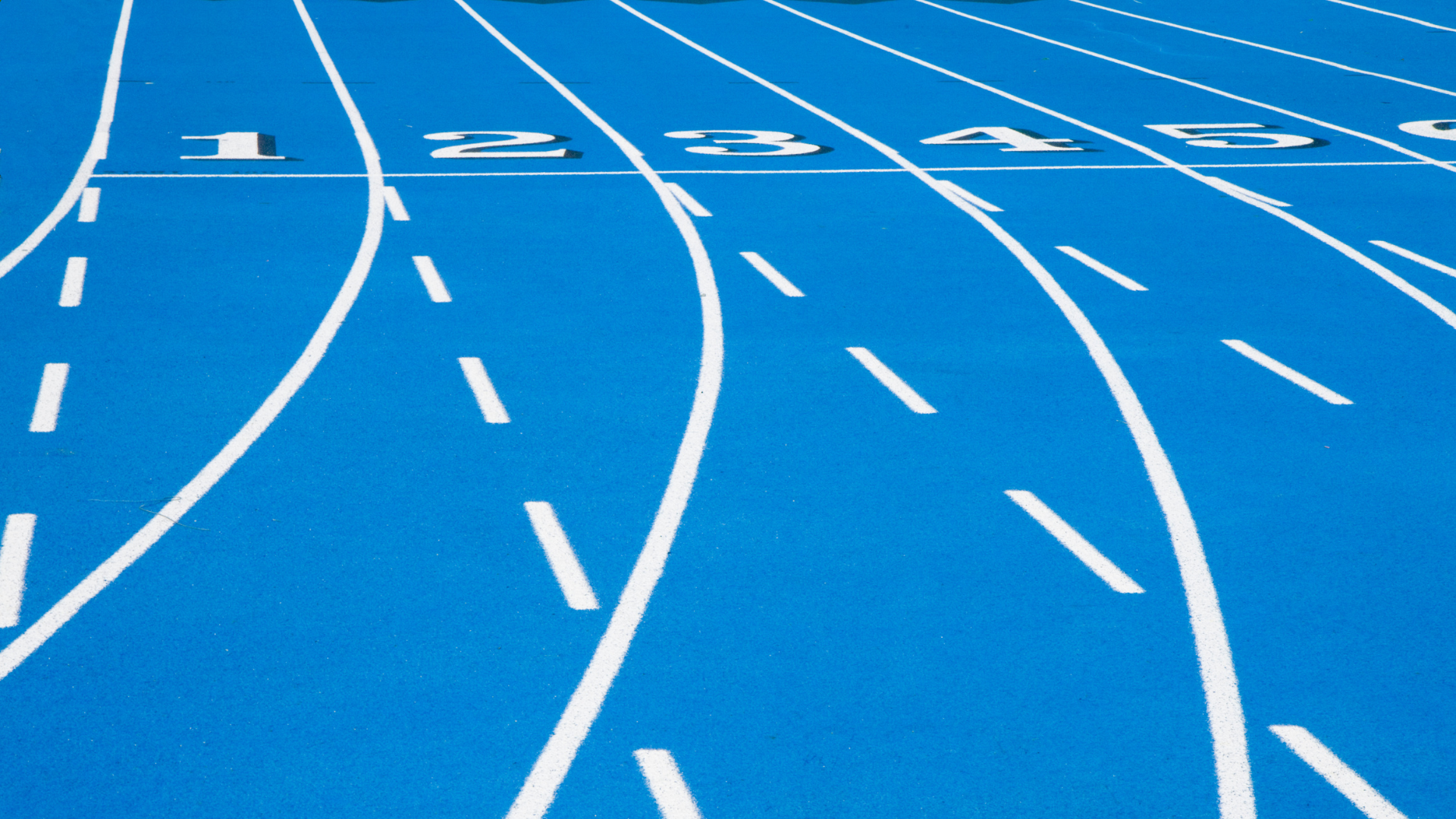 A blue running race track shows different lanes painted with white lines