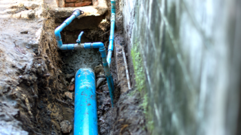A bright blue underground pipe is exposed during some maintenance works