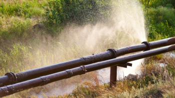 An overground pipe with a leak sprays water into the air