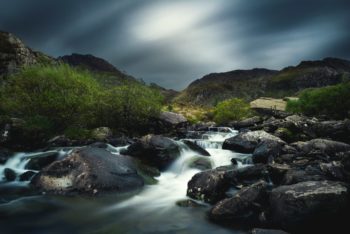 Image of water flowing down rocky landscape, with hills in the background