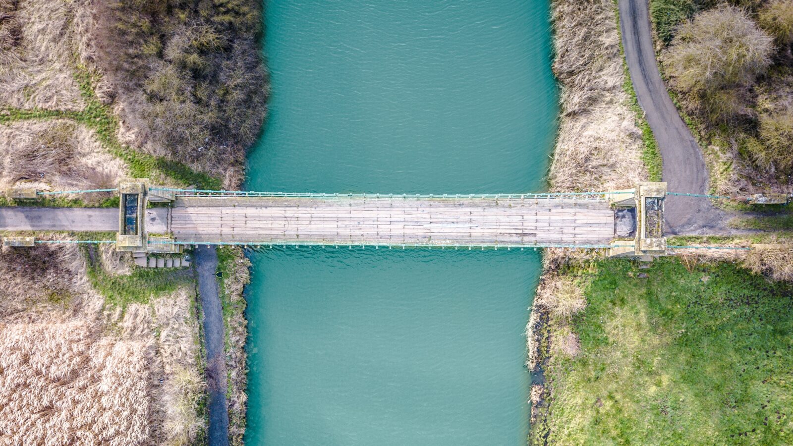 An aerial view of a bridge crossing river full of bright blue water