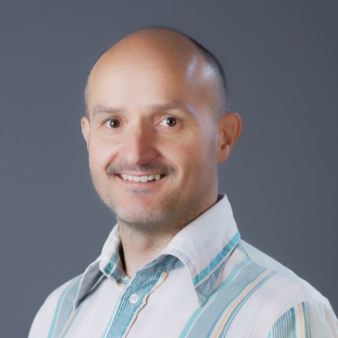 David Clubb wears a striped shirt and smiles at the camera
